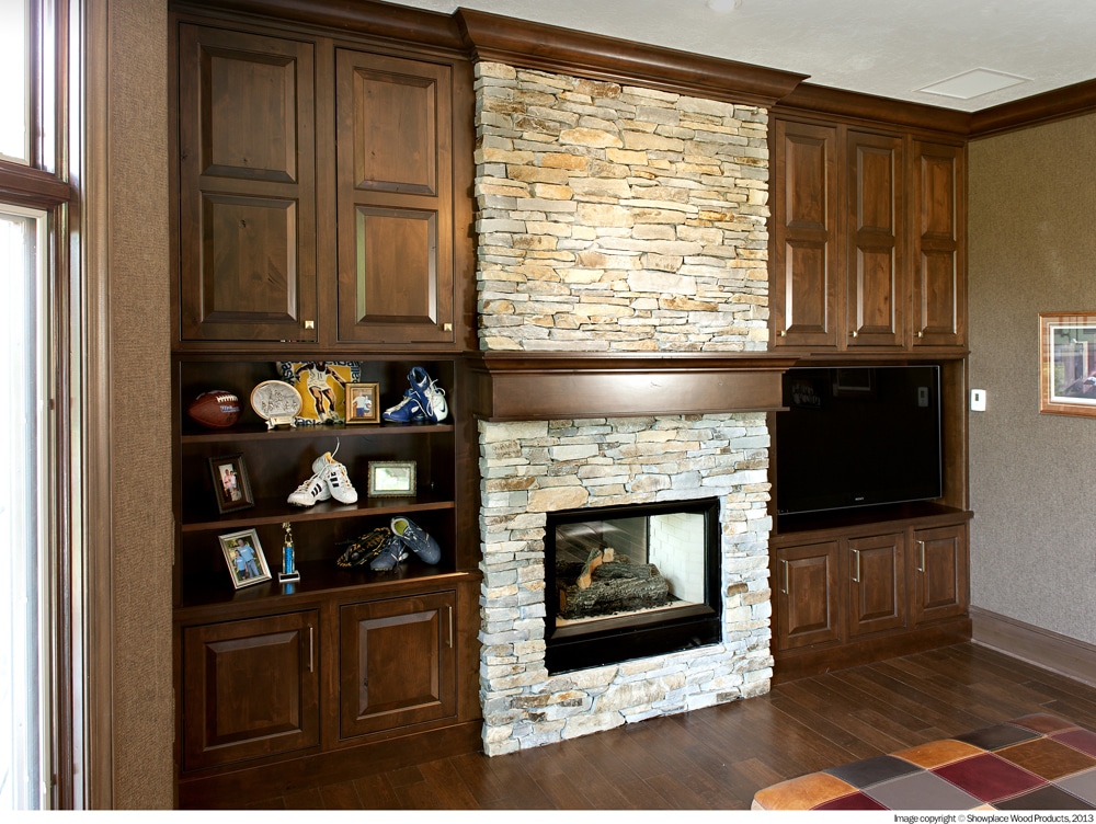 Stone fire place next to wood cabients