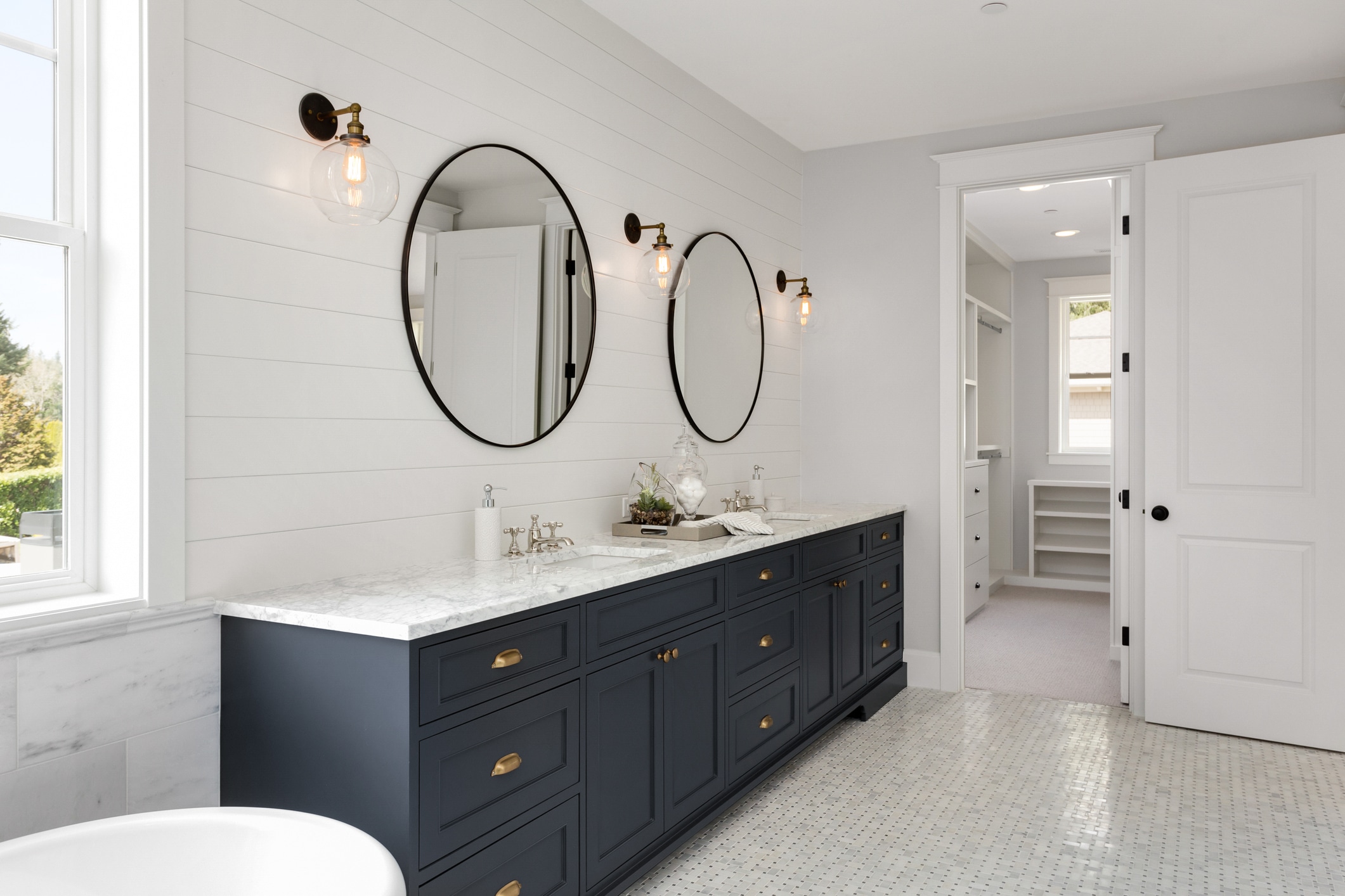 Bathroom in New Luxury Home with Two Sinks and Dark Blue Cabinets. Shows Walk-In Closet